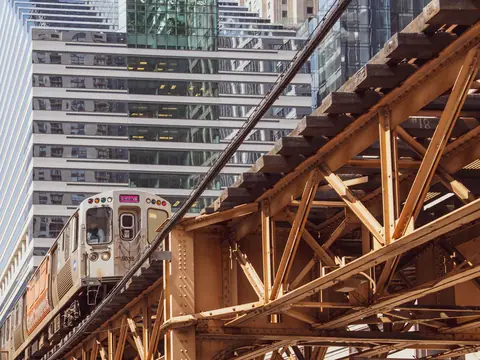 An 'L' train passing under the steel girders of the elevated tracks downtown