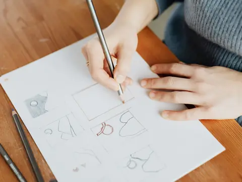 A hand sketching letter shapes with a pencil on paper