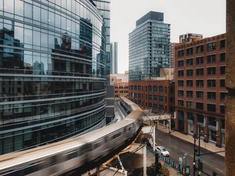 An 'L' train curving between glass and brick buildings in Chicago