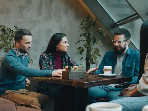 Four people talking around a cafe table
