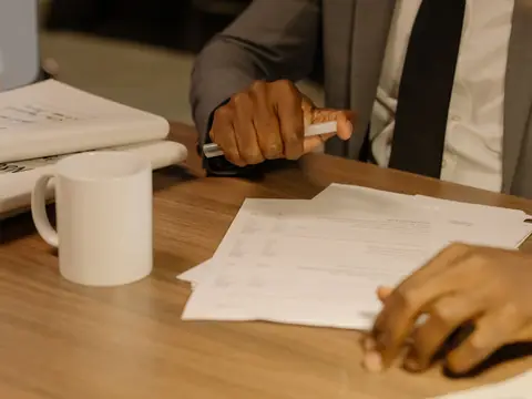 Papers, a pen and a mug on a desk during a meeting