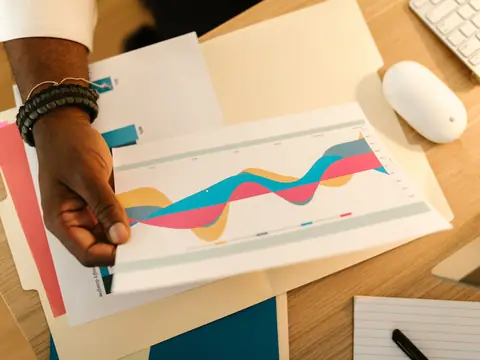 A hand holding a printed report with colorful charts