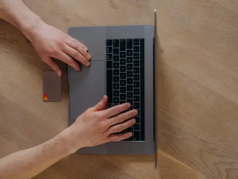 Hands on a laptop keyboard seen from above on a wooden desk