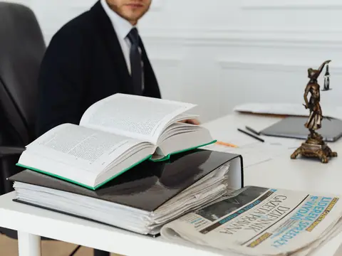 Law books, binders and a scales-of-justice figure on a white desk