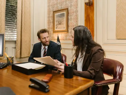 Two people meeting across a wooden desk in a traditional office