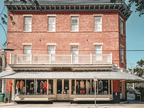 A red brick corner building with shop windows on the ground floor