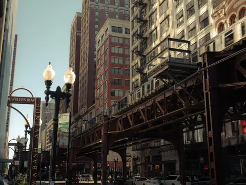 Lamp posts and storefronts under the elevated tracks on a Loop street