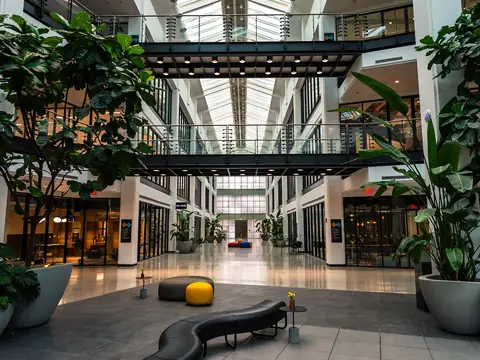 A bright office atrium with plants, seating and a skylight