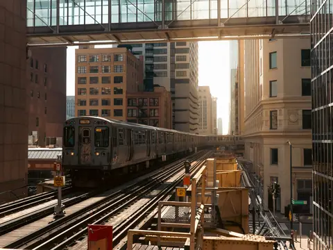 An 'L' train on the tracks between downtown buildings