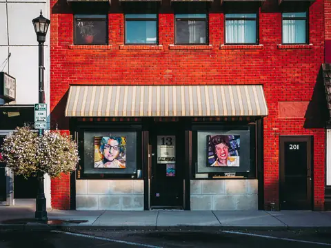 A red brick storefront with art prints in its windows