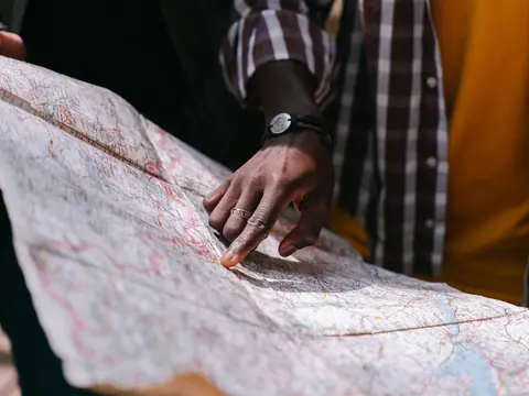 A finger tracing a route on a large paper map