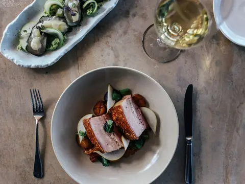 A plated dish, oysters and a glass of white wine on a table