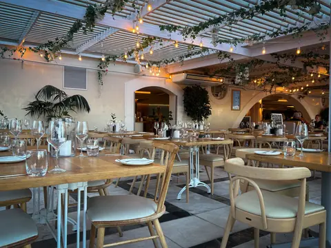 A restaurant dining room with set tables under string lights