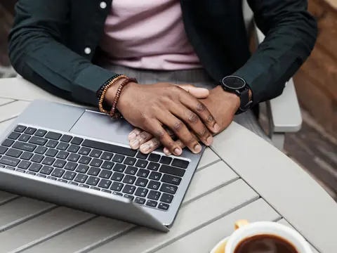 Hands resting on a laptop keyboard at a cafe table