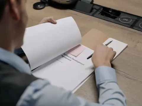 A man reading a printed agreement at his desk