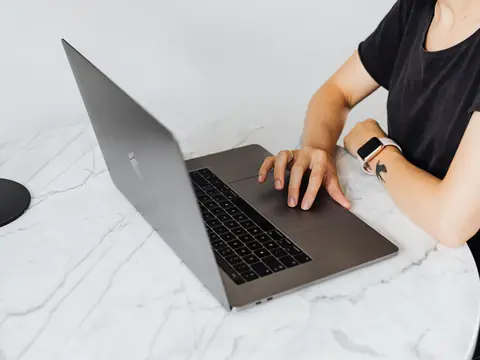 A woman working on a laptop at a marble table