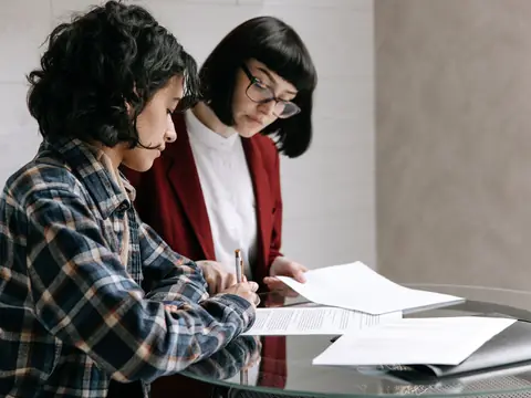 Two women reading through papers together at a table