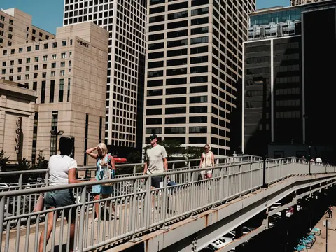 People crossing a bridge between downtown Chicago towers in summer