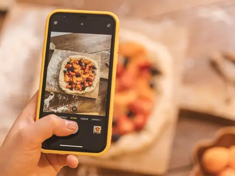 A phone photographing a freshly baked fruit tart