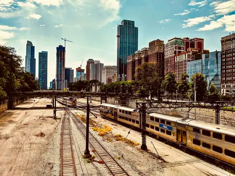 Rail tracks and a commuter train below the Chicago skyline